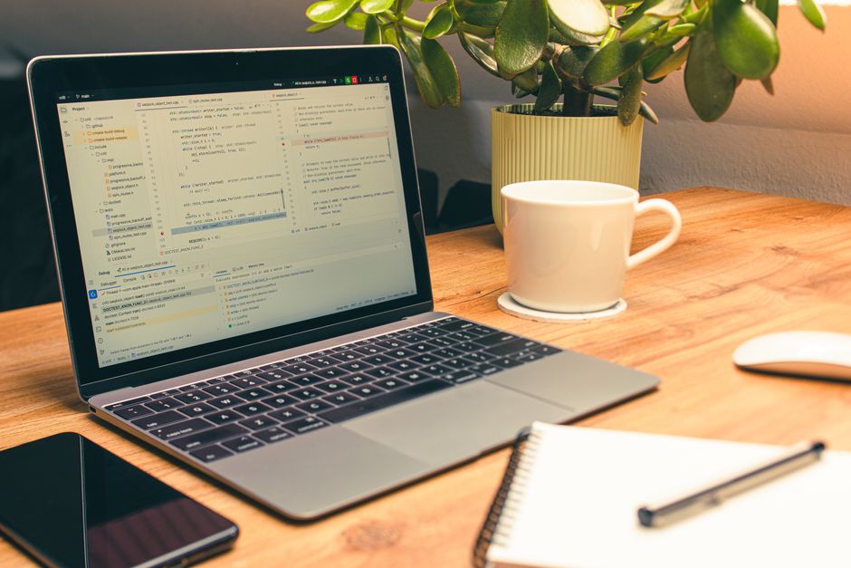 Cozy home office setup featuring a laptop, coffee, and a green plant for productivity.